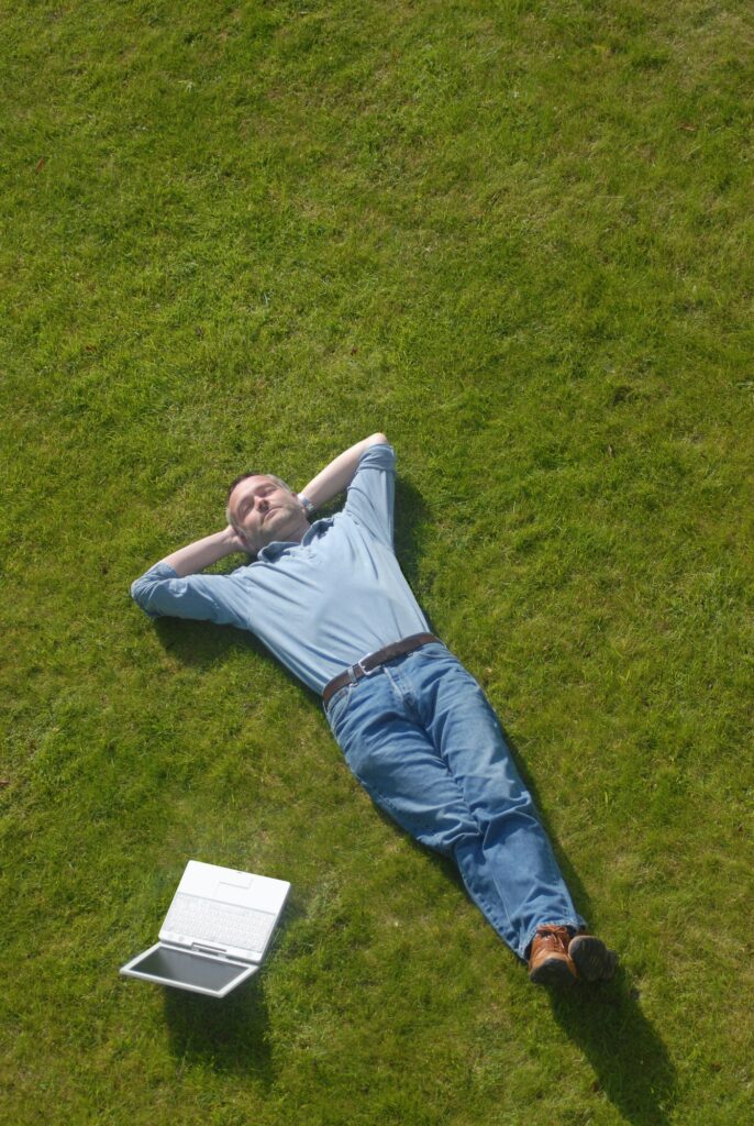 Contented man relaxes on lawn with PC